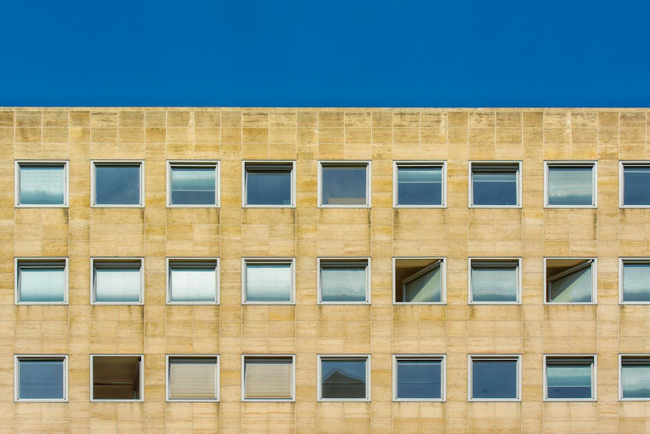 Facade of a modern building featuring symmetrical windows against a clear blue sky.