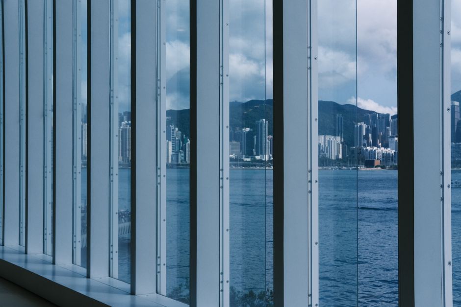 View of city skyline through modern indoor glass windows overlooking the ocean.