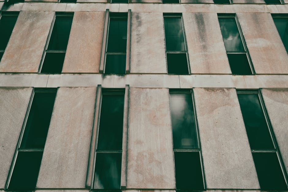 A modern concrete building facade with repetitive windows creating a minimalistic architectural pattern.