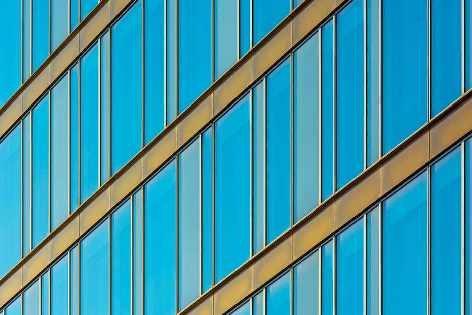 Abstract view of a modern glass facade with blue windows and gold frames.